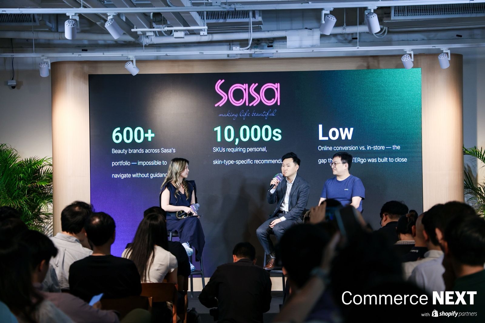 Hong Li speaking into a microphone on a panel at Shopify CommerceNext Hong Kong